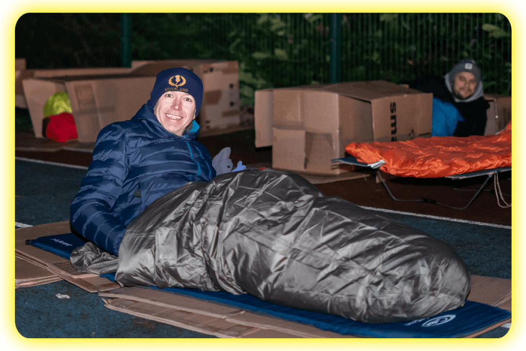 A man in a sleeping bag at the DENS Sleepout