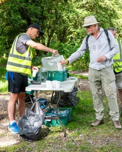 A male volunteer pouring a cup of water for a man