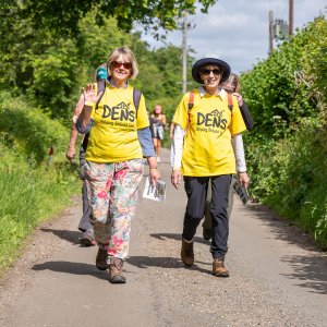 a couple of people in DENS t-shirts walking down a road