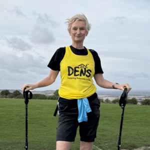 Wendy in a yellow DENS t-shirt and with walking poles